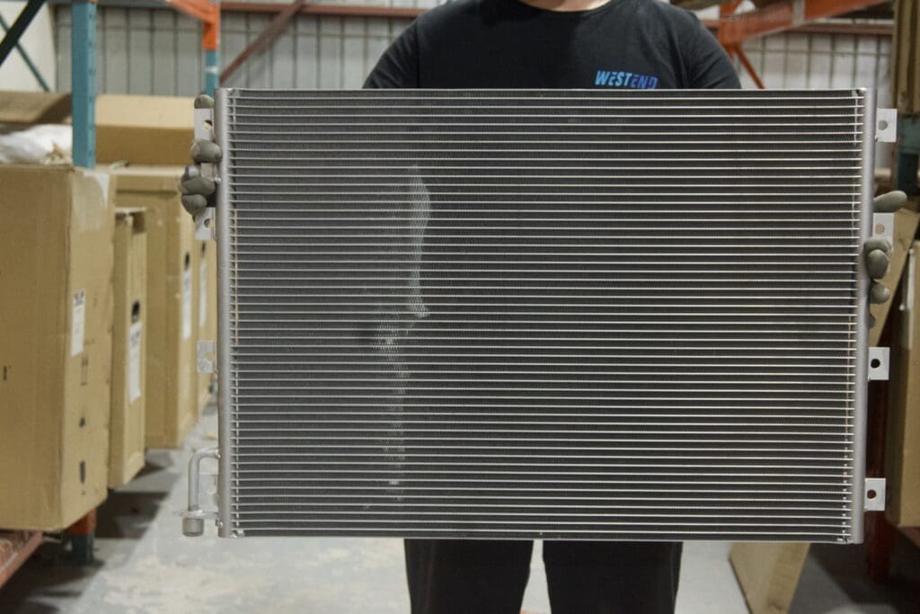 Shop tech holding an A/C condenser